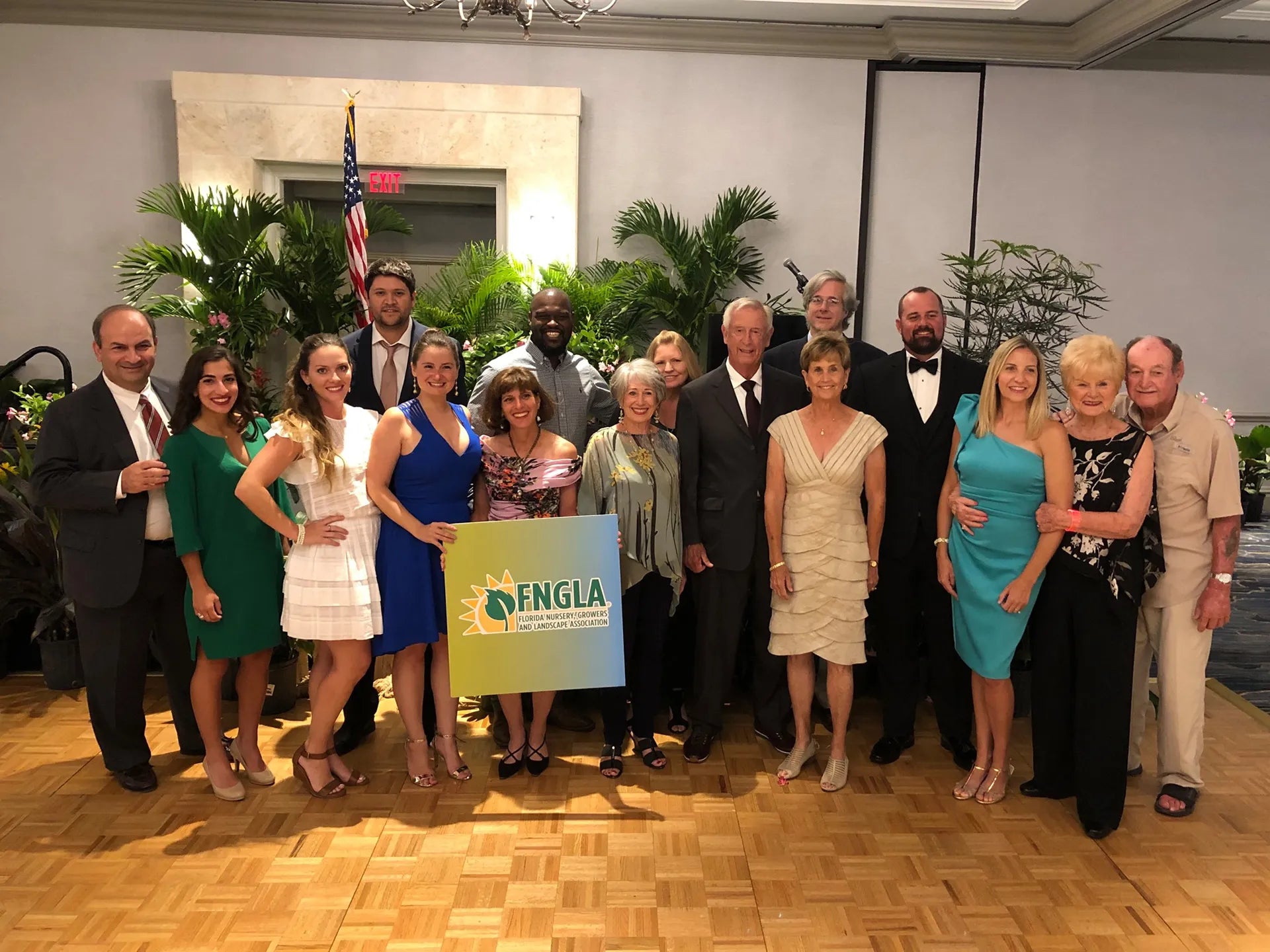 Group of people posing for a photo in a formal setting with an FNGLA sign.