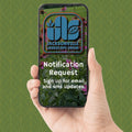 A hand holds a smartphone showing a digital screen with the Jacksonville Landscape Show logo and text reading 'Notification Request' and 'Sign up for email and sms updates.' The background is a green patterned surface.
